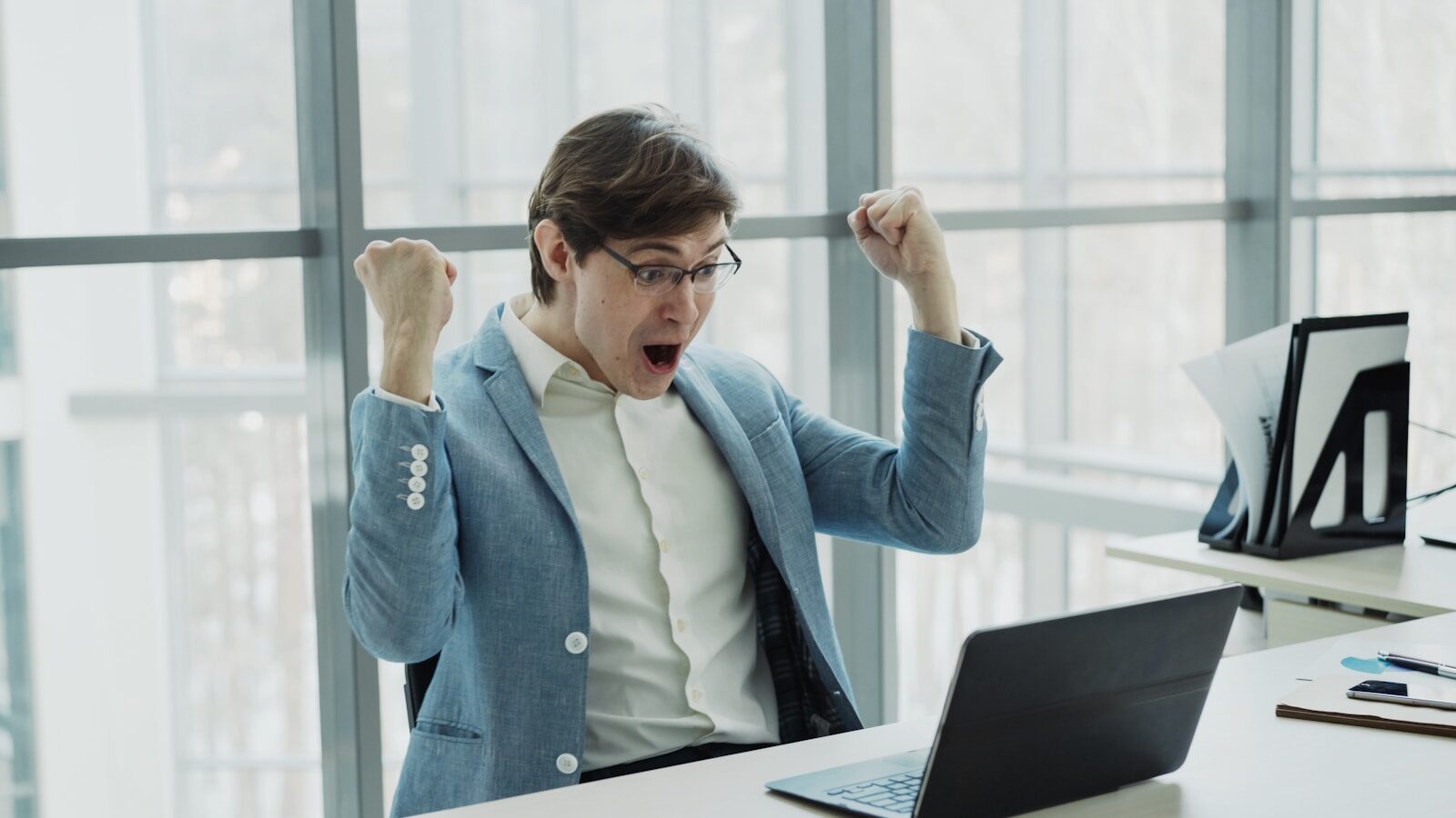 Man in suit celebrating success at office desk